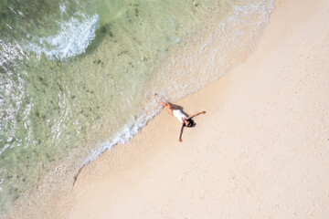 Aerial view, women lounging, sunbathing on the beach and beautiful blue water waves on the island...