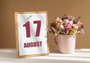 august 17. 17th day of month, calendar date.Bouquet of dead wood in pink mug on desktop.Cork board with calendar sheet on white-beige background. Concept of day of year, time planner, summer month