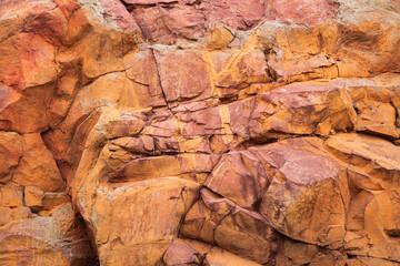 An image of a large red and orange rock wall texture with chips, cracks, stains, and scrapes. 