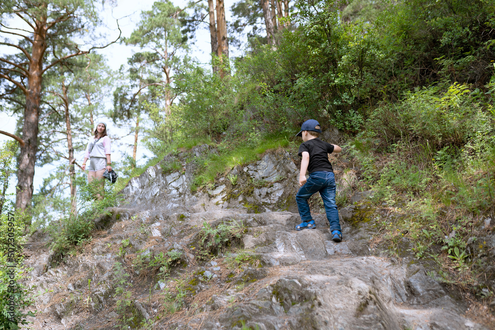 Poster little boy walking with parent in the mountains