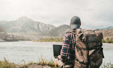 Men with laptop on the beach of river