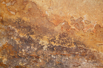 A closeup image of a real red and yellow grunge rock wall texture with chips, cracks, and scrapes. 