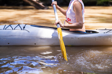 Close up of young woman kayaking along river on summer afternoon. Healthy lifestyle concept.