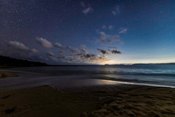 The night sky at the beach and the city lights in the distance