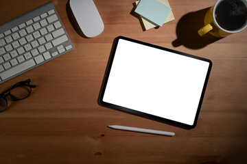 Fototapeta premium Simple workplace with digital tablet, coffee cup, glasses and sticky notes on wooden table. View from above.