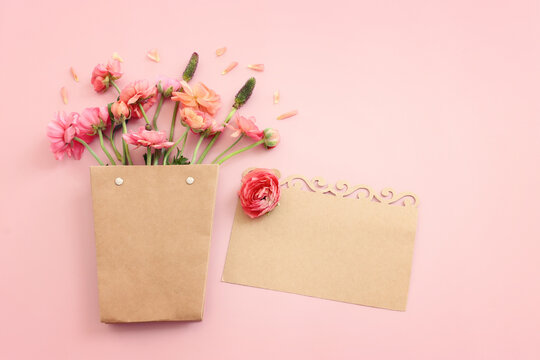 Top view image of pink flowers composition and empty note over pastel background