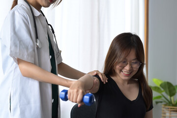 Obraz premium Female physiotherapist giving exercise with dumbbell treatment about arm and shoulder of female patient. Physical therapy concept.