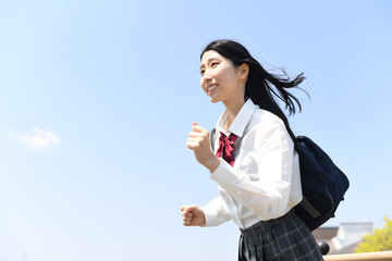 青空の下で走る女子学生