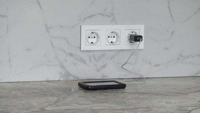 charging smartphone on wooden table. Electric socket with connected phone charger
