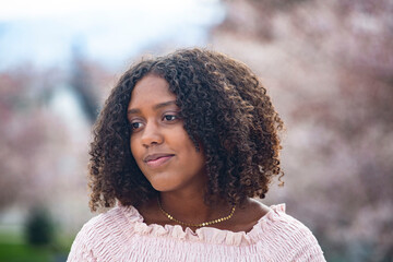 Charming Beautiful Black teen girl with big curly hair.  Thinking and being contemplative. Outdoor candid portrait of a natural beauty - Powered by Adobe
