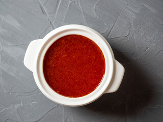 Close-up of soup borscht in a white ceramic soup bowl on a gray textured background. Traditional soup for Russia and Ukraine. Top view, flat lay