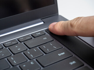 Close-up of a finger pressing the laptop power button. Fingerprint scanner. Modern devices for work and leisure, selective focus