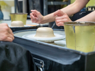 Close-up of people's hands making an object out of raw clay on a potter's wheel. Conducted master classes and workshops. Hobby, selective focus