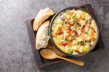 Homemade vegetable potatoes soup with smoked bacon closeup in the bowl on the wooden tray. Horizontal top view from above