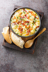 Polish Potato Soup With bacon Traditional Kartoflanka closeup in the bowl on the wooden tray. Vertical top view from above