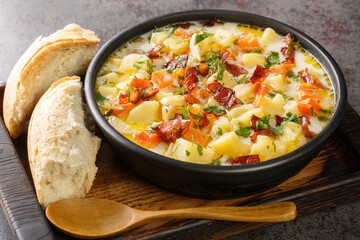 Homemade vegetable potatoes soup with smoked bacon closeup in the bowl on the wooden tray. Horizontal