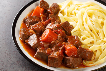 Daube de Boeuf Provencale slow cooked Rich Beef Stew with noodles closeup in the plate on the table. Horizontal