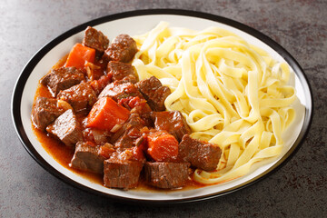 Provencal Beef Stew Daube served with noodles closeup in the plate on the table. Horizontal