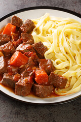 Daube Provencal classic French stew beef is slow simmered to tenderness served with noodles closeup in the plate on the table. Vertical