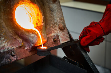 Worker takes sample of liquid gold from furnace for tests