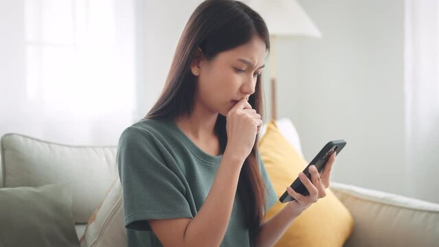 Worried young woman looking at smartphone screen, dissatisfied with bad news message, spam or scam sms. Bad mood lifestyle concept.
