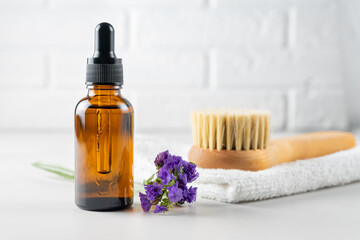 Obraz na płótnie Canvas Spa body care concept. Anti cellulite cosmetics, Wooden brush for dry massaging, essential oil and white cotton towel on a bathroom table. Skin care concept