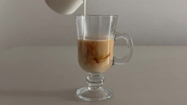 Pouring milk into glass cup with coffee to make "London Fog Coffee"