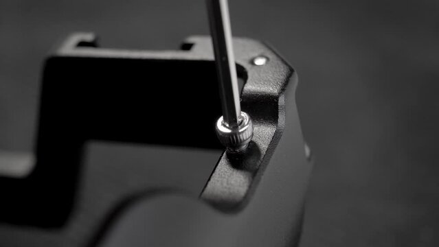 Unscrewing metal black hardware with allen key and screw close up. Using hex key. Hexagonal wrench. Macro