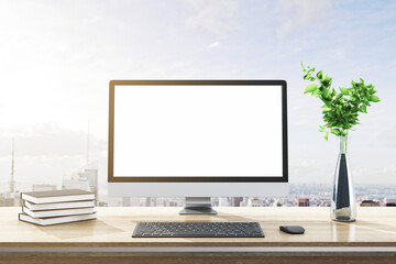 Close up of modern designer desktop with books, empty white computer screen, decorative plant, supplies and bright city and sky view background. Mock up, 3D Rendering.