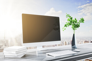 Close up of modern designer desktop with books, clean computer screen, decorative plant, supplies and bright city and sky view background. Mock up, 3D Rendering.