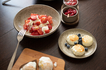 Tomatoes with burrata cheese, cheese pancakes and other food served in beautiful plates on table. Focus on tomatoes