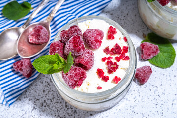 Overnight cheesecake oatmeal. Cheesecake morning breakfast layered parfafait dessert with homemade cottage cheese, mascarpone, oats and fresh raspberries, on sunny white concrete background copy space
