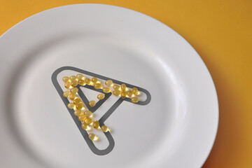 Vitamin A icon from capsules on a plate. Vitamin A deficiency in humans