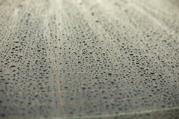 Drops of water on black surface. Car parts in rain.