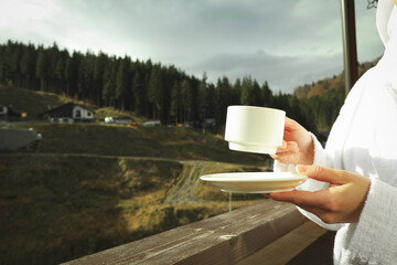 Woman with cup of coffee on balcony in ski resort