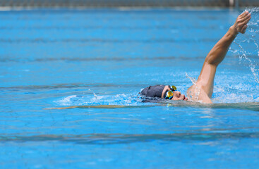 young swimmer in goggles exercising in swimming pool