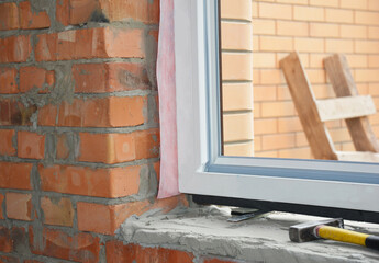 Windows installation. Inserting a upvc plastic window frame in a newly constructed brick house.