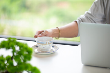 Business man holding a cup of coffee and office desk table with laptop computer. Business concept