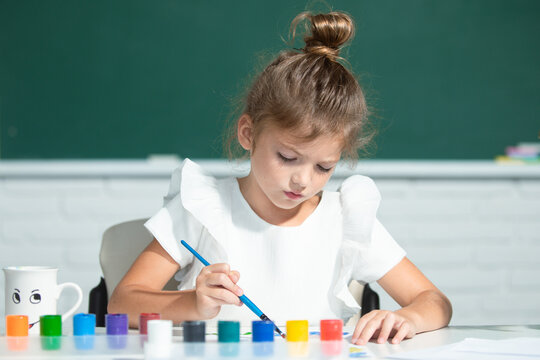 Little girls drawing a colorful pictures with pencil crayons in school classroom. Painting kids. Early childhood education.