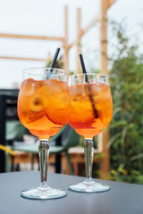 Two glasses of Aperol Spritz served on the terrace of modern bar. Popular Italian wine based cocktail and summer aperitif refreshing drink prepared with prosecco wine, bitter liqueur and soda water.