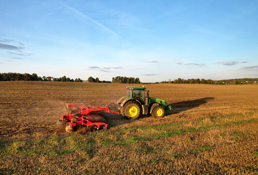 Plowing field. John Deere Tractor with disc cultivator Vaderstad on cultivating field. Agricultural tractor on cultivation field. Soil Tillage and sowing seeds. Russia, Smolensk, September 07, 2021.