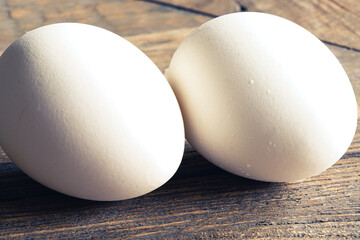Two Fresh White Eggs on a wooden rustic background. Close up with shallow depth of field.