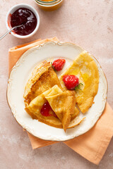 Overhead view of crepes and strawberry jam on plate
