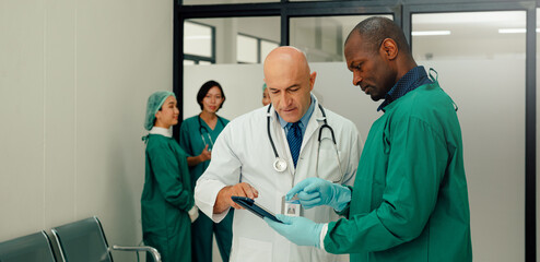 Male Surgeon and Doctor Consult Using Digital Tablet Computer while Talking about Patient's Health.