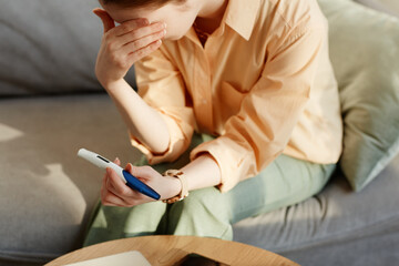 Close up of depressed young woman holding pregnancy test at home and crying, copy space