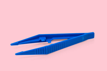 Blue plastic sterile surgical tweezers isolated on pink background.