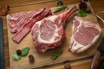 Mixed fresh meat Tomahawk beef, Cross Cut Short Ribs beef, Sliced brisket beef, T-bone steak beef on wooden background.