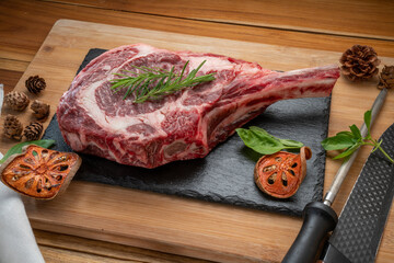 Tomahawk beef steak with rosemary on black plate, Fresh Tomahawk beef on wooden background.
