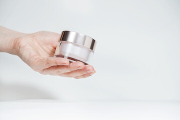 Female hand holding mockup unbranded plastic cosmetic tube. Flacon for cosmetic cream, toiletry. Skincare and beauty concept with copy space. Bottle for professional cosmetics product, on white.