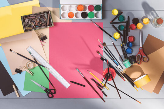 Drawing or painting in art studio top view. Blank paper mock-up on gray wooden table or floor background. Flat lay creative concept image with drawing and painting accessories